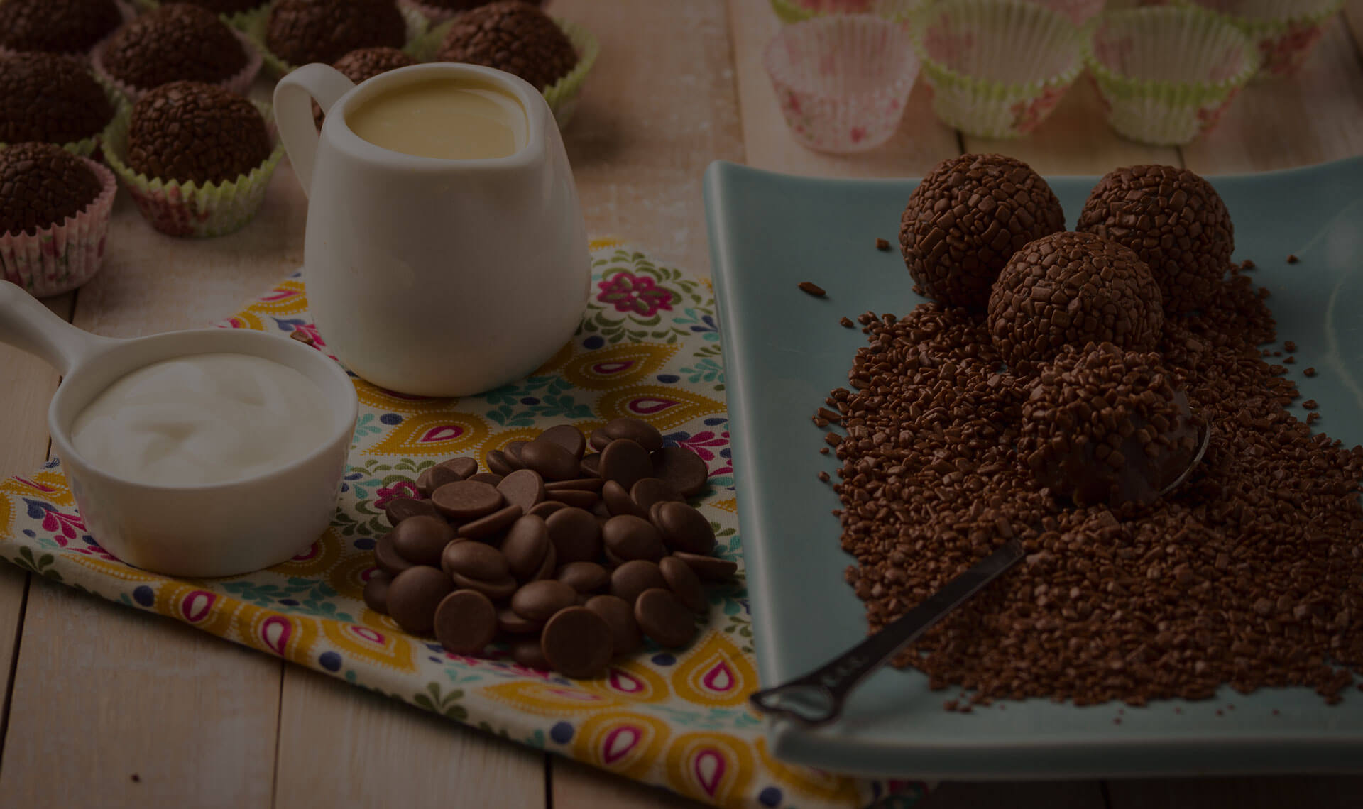 Brigadeiro on a blue plate with dark chocolate chips and heavy cream on a placemat.